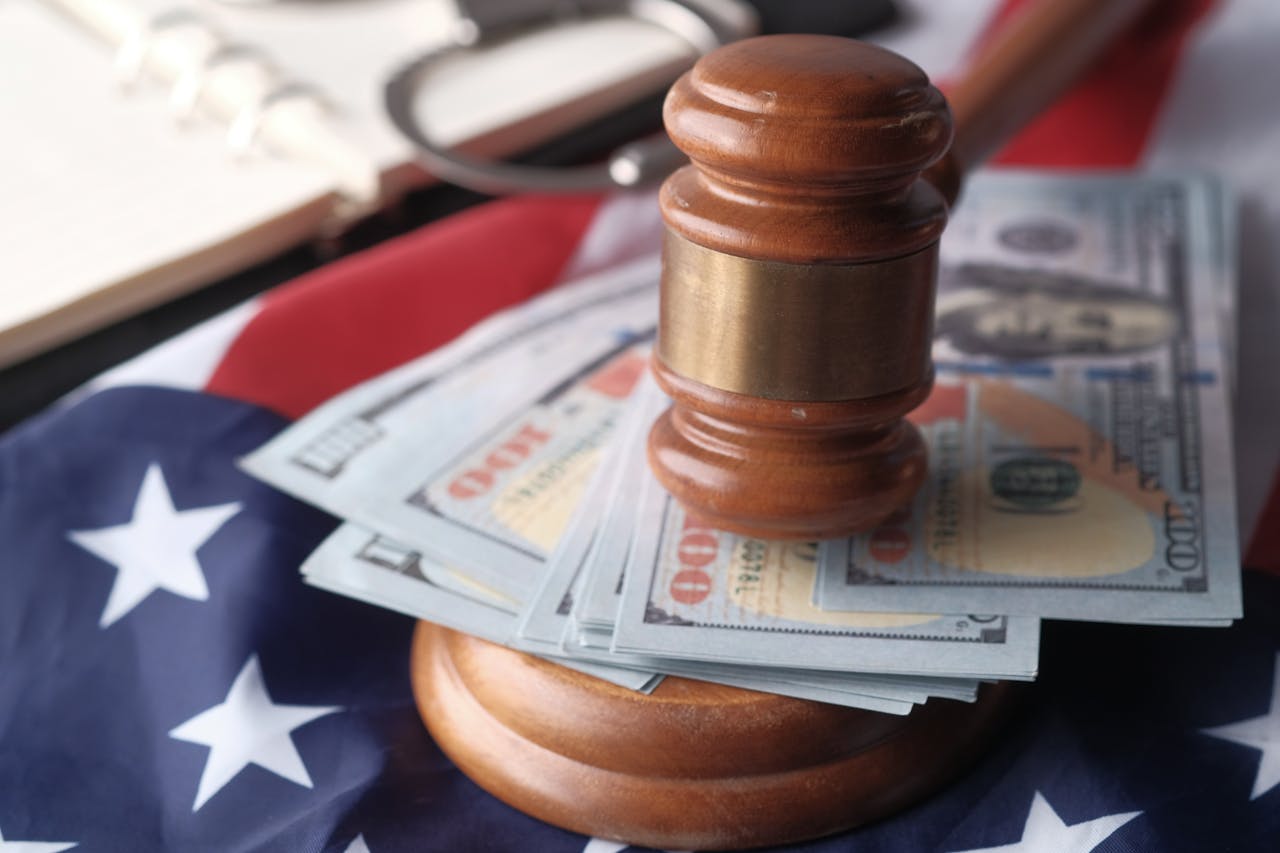 Close-up of a judges gavel resting on US dollar bills and an American flag, symbolizing justice and finance.